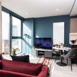 Modern studio apartment interior at 50 Holland Street, featuring a red sofa, dining area, and large windows with city views, highlighting pet-friendly, furnished living in Glasgow's cultural quarter.