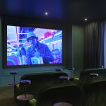 Modern cinema room with plush seating, vibrant screen displaying a film, and ambient lighting, part of the studio apartment amenities at 50 Holland Street, G2 4BD, available to let.