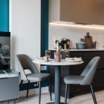 Modern studio apartment interior featuring a round dining table with two grey chairs, equipped kitchen area, and stylish decor, highlighting the furnished living space at 50 Holland Street, Glasgow.