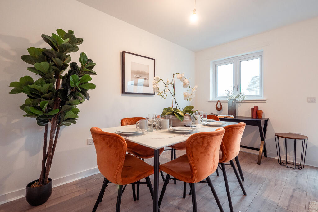 Dining area of a 4-bedroom terraced house in South Queensferry, featuring a marble table set for dining, orange velvet chairs, a decorative plant, and natural light from windows, highlighting the unfurnished accommodation available for rent.