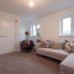 Living room of a 4-bedroom unfurnished terraced house in South Queensferry, featuring a comfortable sofa with decorative cushions, a stylish armchair, and natural light from windows.