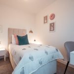 4-bedroom unfurnished terraced house bedroom in South Queensferry, featuring a single bed with decorative pillows, bedside table, framed wall art, and stylish chair.