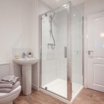Modern bathroom featuring a glass shower enclosure, sink with toiletries, and stylish flooring, showcasing the amenities of a 4-bedroom terraced house in South Queensferry available for rent.