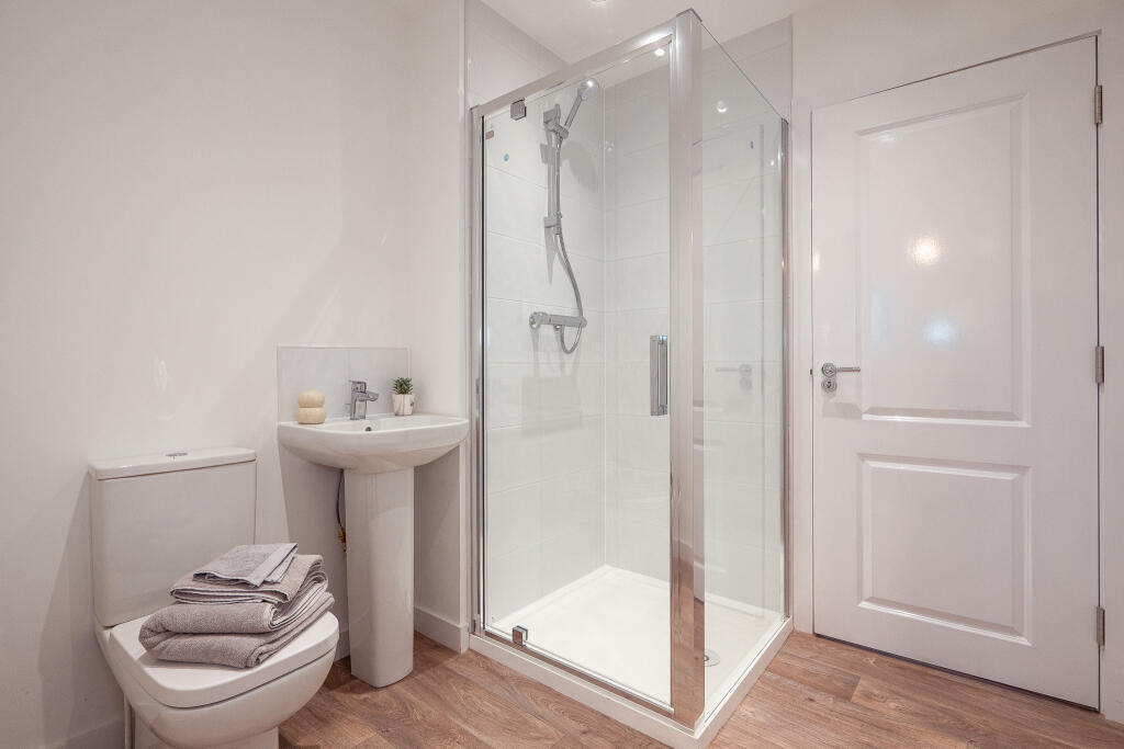 Modern bathroom featuring a shower cubicle, sink, and toilet with neatly folded towels, ideal for the unfurnished 4-bedroom terraced house in South Queensferry available for rent.