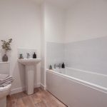 Modern bathroom featuring a bathtub, pedestal sink, and decorative plants in a 4-bedroom unfurnished terraced house in South Queensferry.