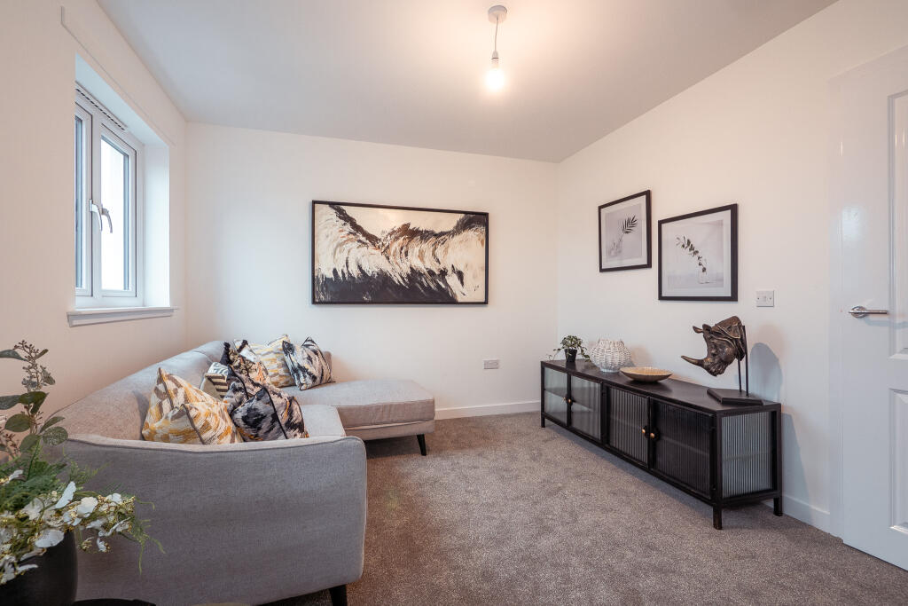 Living room of a 4-bedroom unfurnished terraced house in South Queensferry, featuring a grey sofa with patterned cushions, wall art, and a modern sideboard against a light-coloured wall.