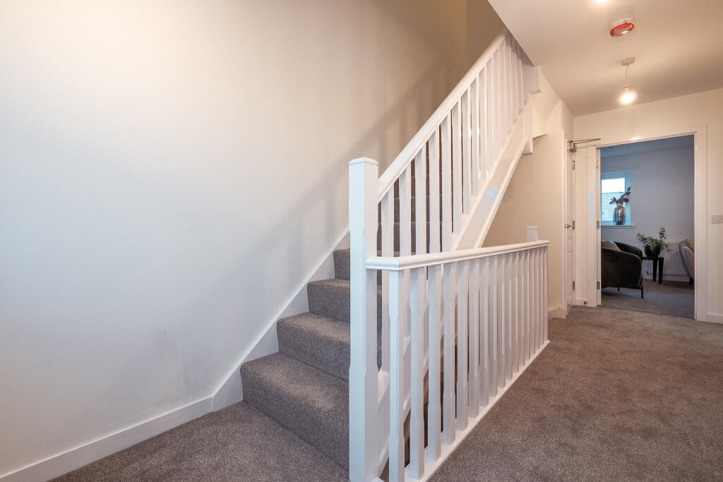 Staircase leading to upper floor in an unfurnished 4-bedroom terraced house in South Queensferry, featuring neutral decor and carpeted flooring.
