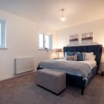 Modern bedroom in unfurnished 4-bedroom terraced house, featuring a double bed, bedside lamps, and decorative artwork, located in South Queensferry.