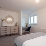 4-bedroom unfurnished terraced house interior with a double bed, dresser, mirror, and desk in a well-lit room, showcasing modern accommodation features in South Queensferry.