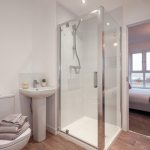 Modern bathroom featuring a glass shower enclosure, pedestal sink, and neutral decor, highlighting the unfurnished 4-bedroom terraced house available for rent in South Queensferry.
