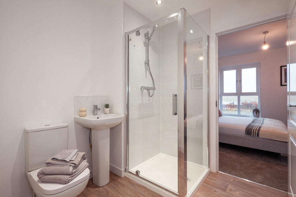 Modern bathroom with shower enclosure, toilet, and sink, showcasing towels and a plant, adjacent to a bedroom in a 4-bedroom terraced house in South Queensferry.