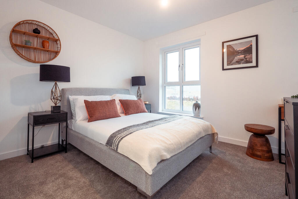 Modern bedroom featuring a double bed with decorative cushions, bedside tables with lamps, a wall shelf displaying decorative items, and large windows providing natural light, suitable for the unfurnished 4-bedroom terraced house for rent in South Queensferry.
