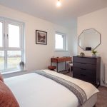 4-bedroom unfurnished terraced house bedroom with double bed, modern decor, large windows, and dresser, showcasing rental property in South Queensferry.