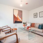 Living room of a 4-bedroom terraced house in South Queensferry, featuring a modern sofa, armchairs, glass coffee table, and contemporary artwork on the wall.