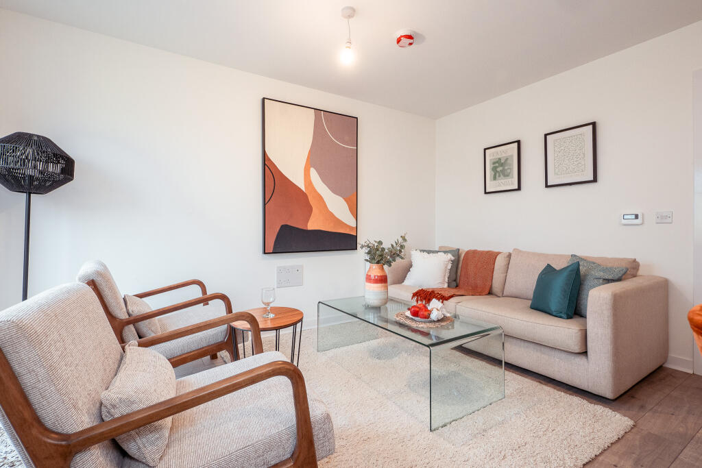 Modern living room with neutral decor, featuring a glass coffee table, a beige sofa with cushions, two armchairs, and decorative art on the wall, ideal for the unfurnished 4-bedroom terraced house in South Queensferry.